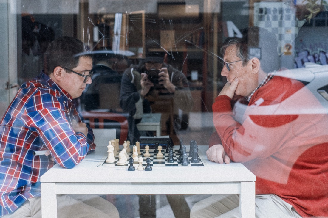 Dos socios jugando una partida, vistos desde la calle